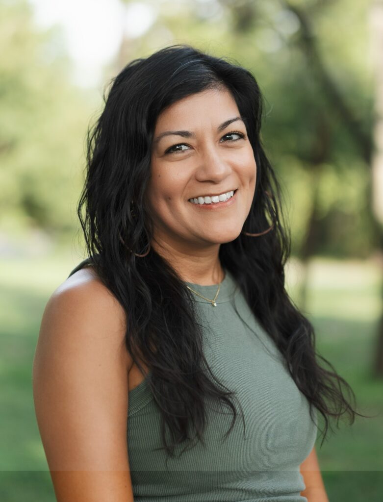Smiling woman with dark hair and dimples in a green tank top outdoors