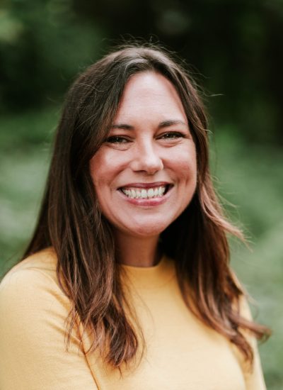 Smiling woman in yellow sweater, portrait of a graduate.